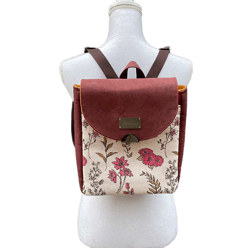 Un sac à dos fabriqué avec un tissu d'écharpe à motifs floraux dans des tons roses sur fond écru et en liège couleur brique.