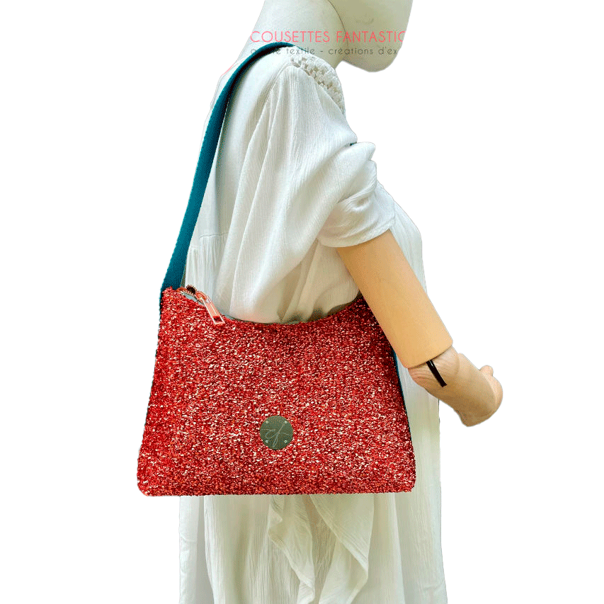 Un petit sac bandoulière zippé fabriqué à partir d'un tissu extensible avec du bouclé métallique cuivré, du simili bleu turquoise, et une doublure orange clair lumineuse.