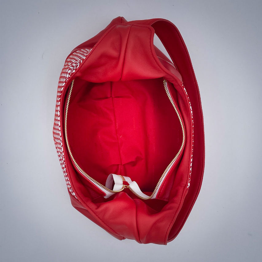 Un sac d'épaule fabriqué à partir d'un cuir rouge et d'un cuir rouge imprimée pied de poule blanc, avec une doublure rouge siglée Sonia Rykiel.