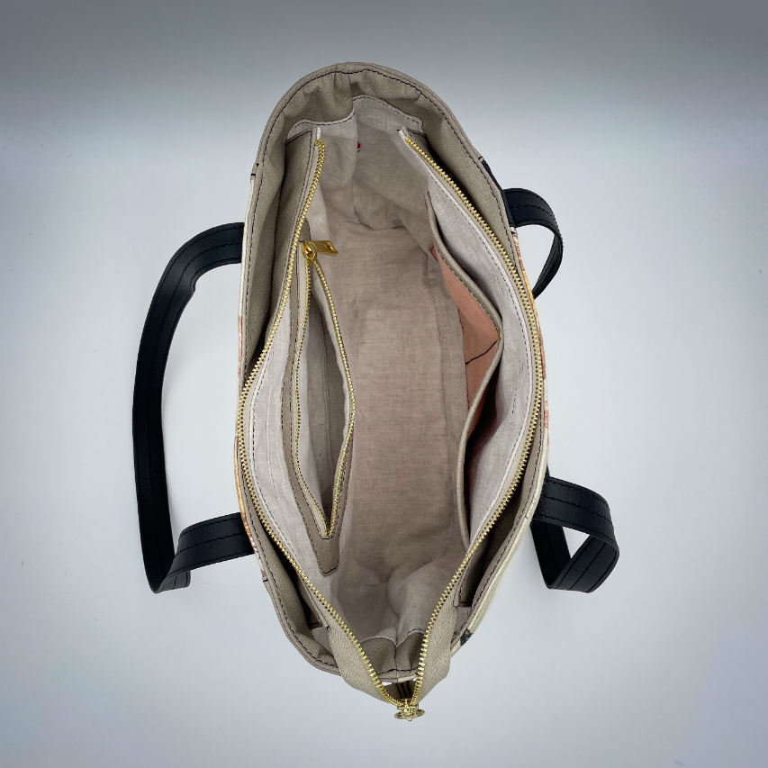 Un grand sac d'épaule type cabas zippé, fabriqué à partir d'un tissu épais au motif d'oiseaux sauvages associé à des simili noir et taupe, et une doublure lin crème chiné et corail.