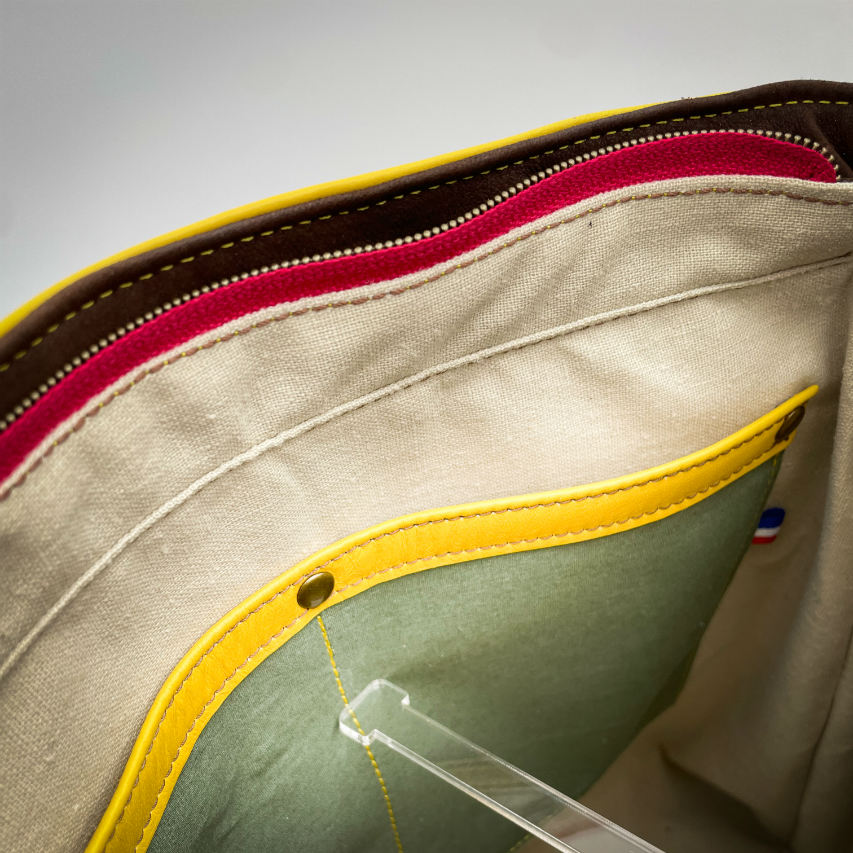 Un sac d'épaule fabriqué à partir de cuirs chocolat et jaune mariés à une toile fleurie avec des fleurs roses et jaunes.
