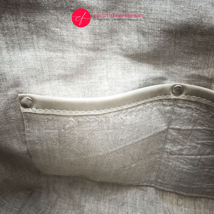Un sac à bandoulière fabriqué en laine bleu marine et damas de coton blanc.