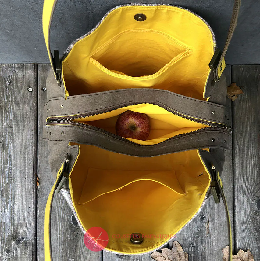Un sac d'épaule fait à partir de papier lavable couleur chocolat, écharpe de portage beige rosé chiné, au motif d'oiseaux blancs dans des branchages blancs et jaune, avec une doublure jaune vif.