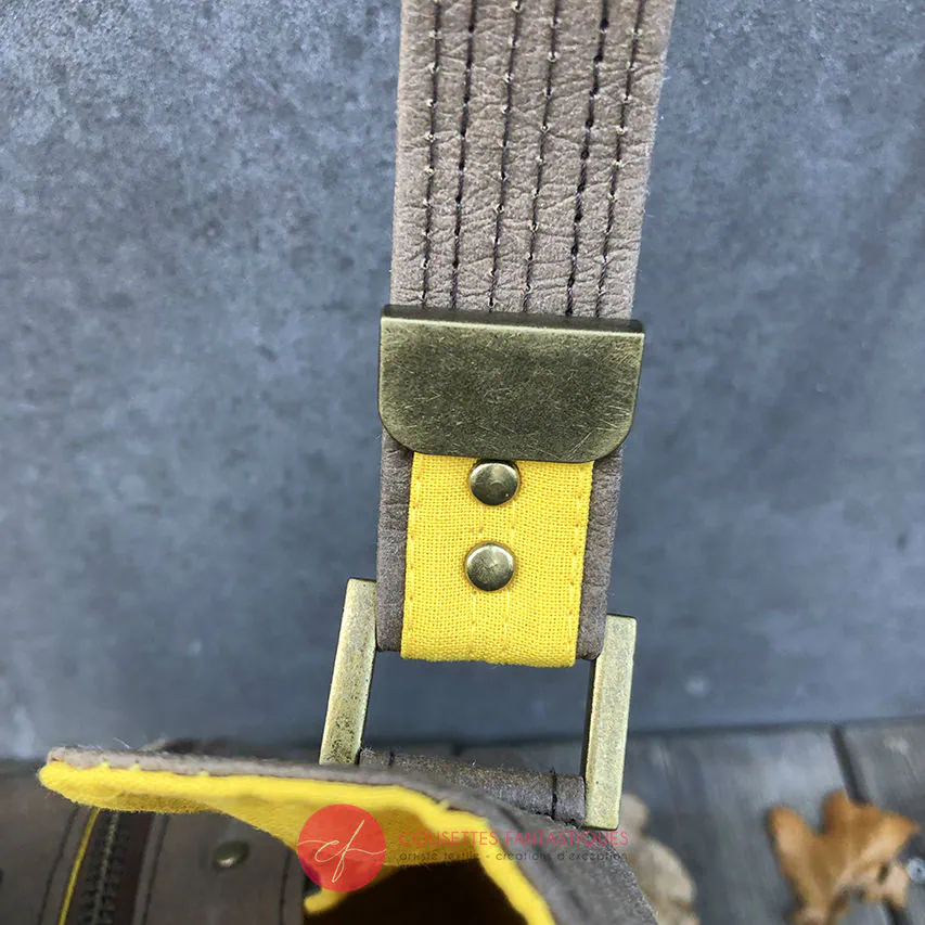 Un sac d'épaule fait à partir de papier lavable couleur chocolat, écharpe de portage beige rosé chiné, au motif d'oiseaux blancs dans des branchages blancs et jaune, avec une doublure jaune vif.