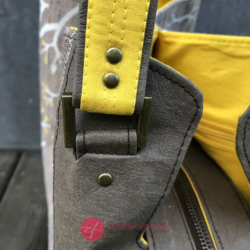 Un sac d'épaule fait à partir de papier lavable couleur chocolat, écharpe de portage beige rosé chiné, au motif d'oiseaux blancs dans des branchages blancs et jaune, avec une doublure jaune vif.