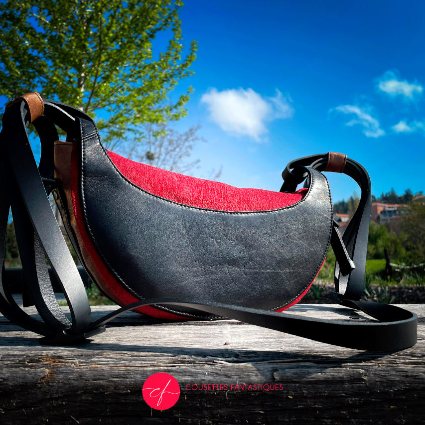 A shoulder bag made of black and caramel leathers, red and black velvet upholstery fabric, and red and black satins.