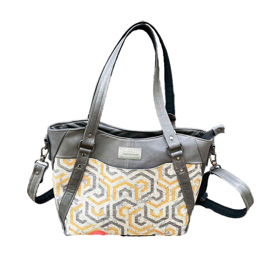 Un sac d'épaule fait en écharpe de portage gris, moutarde et écru avec motifs géométriques, et cuir d'agneau gris.