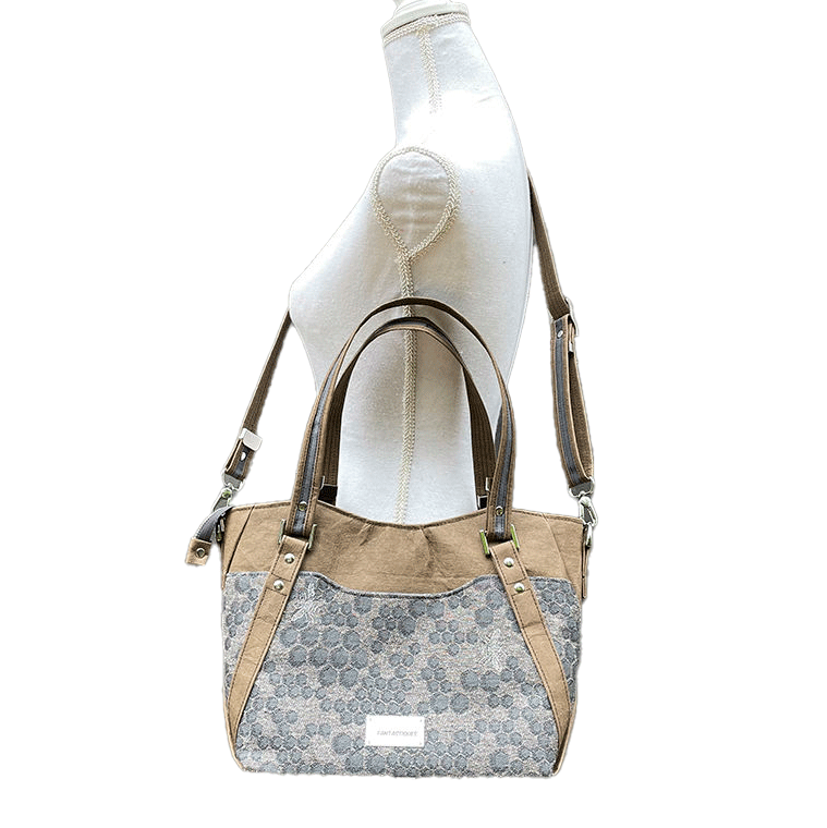 Un sac d'épaule fait avec du tissu d'écharpe gris au motif de ruche et d'abeilles, et du papier lavable marron.