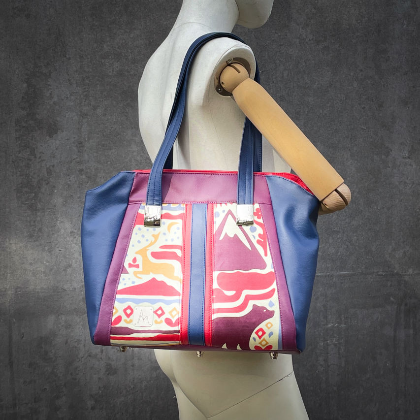 Un sac d'épaule fabriqué à partir d'un foulard en soie avec des motifs issus du folklore Scandinave, associé à des similis rouge, bleu et violet.