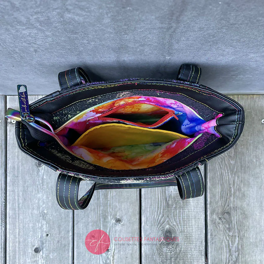 Anses bicolores/bi-matières, bouclerie luxe coloris arc-en-ciel, simili de récup' au toucher velours, et écharpe de portage au motif fantaisiste.