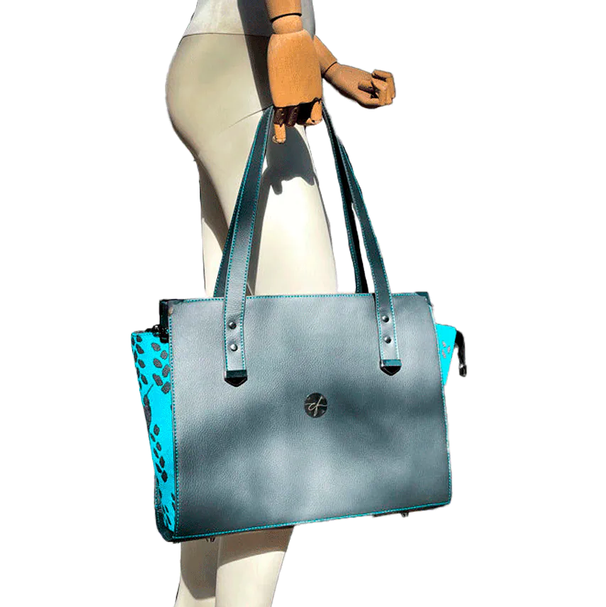 Un sac d'épaule fabriqué à partir d'un tissu de portage turquoise avec des motifs de colibris et de pétales, associé à du simili gris et turquoise.