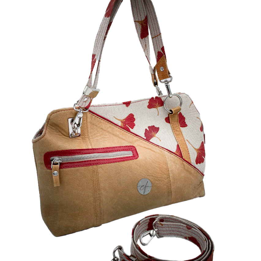 Un sac à main fait d'un cuir de couleur camel et une toile en polycoton avec un motif de feuilles de Ginkgo Biloba rouges.