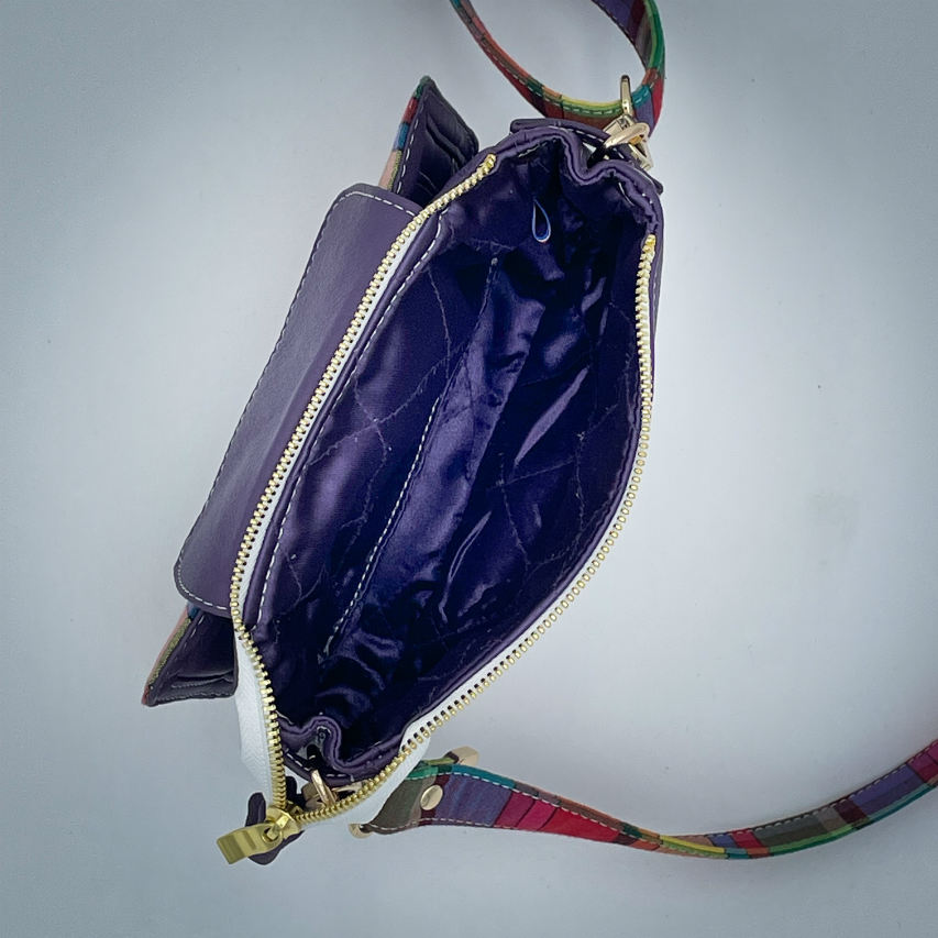 Un sac portefeuille constitué de cuir violet et de toile de madras multicolore.