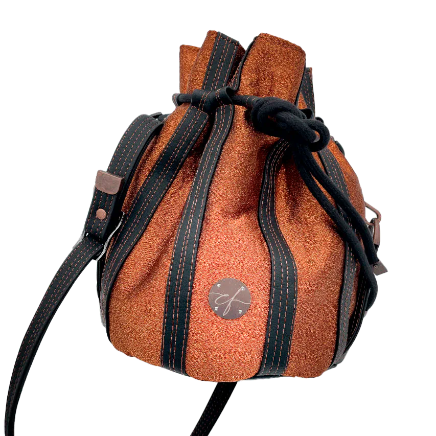 Un sac seau brillant fabriqué avec un tissu lamé bronze brillant et du simili noir mat et doux.