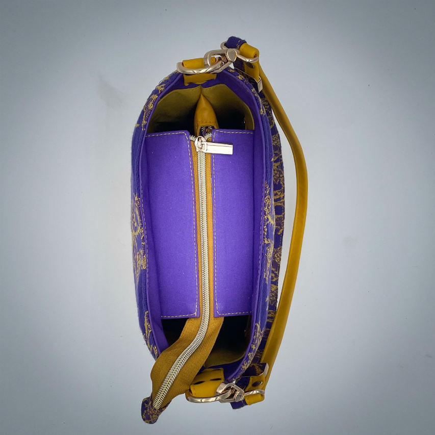 Un sac seau fabriqué avec de l'écharpe de portage au motif de chardons jaunes sur fond violet et du cuir d'agneau jaune.