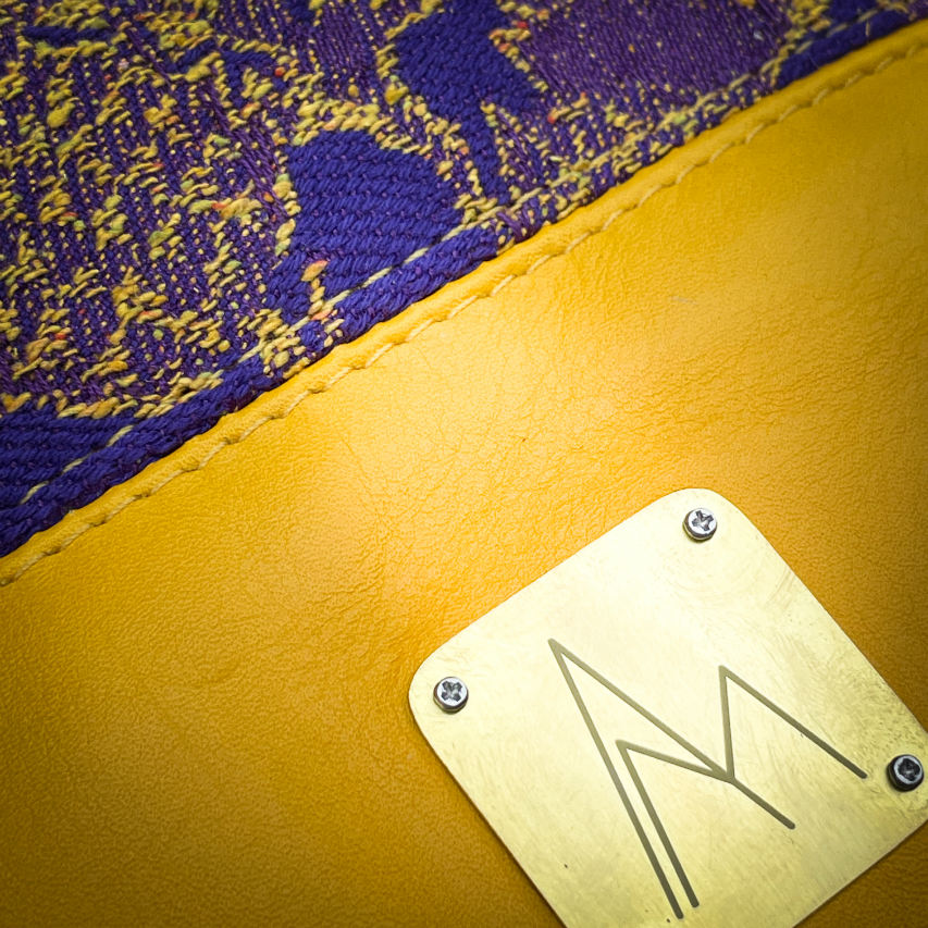 Un sac seau fabriqué avec de l'écharpe de portage au motif de chardons jaunes sur fond violet et du cuir d'agneau jaune.