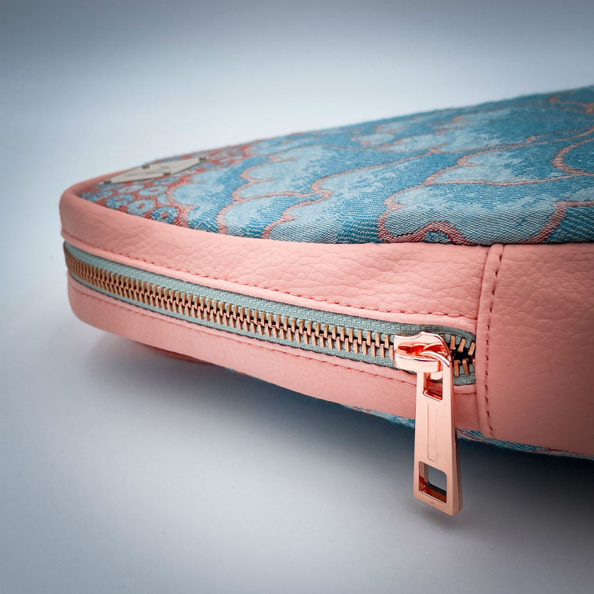 Un sac à dos fait de simili coloris pêche et d'une écharpe de portage dans les tons rose et turquoise avec un motif floral vintage.