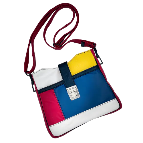Un sac besace composé de différents cuirs bleu roi, rouge profond, jaune vif, blanc et noir.