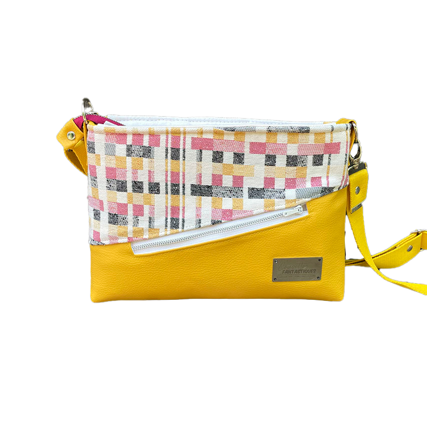 Un sac à bandoulière rectangulaire fabriqué à partir d'écharpe de portage noir, blanc, rose et jaune à motif géométrique, et de simili jaune tournesol.