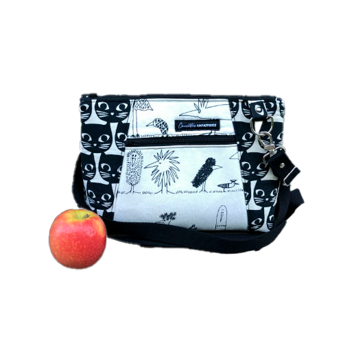 Un sac en bandoulière trapézoïdal fabriqué à partir de toile en coton noir et blanc avec des motifs stylisés de chats et d'oiseaux, assorti à de la cretonne de coton à thème aviaire à l'intérieur.