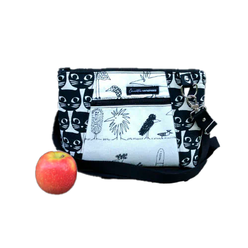 Un sac en bandoulière trapézoïdal fabriqué à partir de toile en coton noir et blanc avec des motifs stylisés de chats et d'oiseaux, assorti à de la cretonne de coton à thème aviaire à l'intérieur.