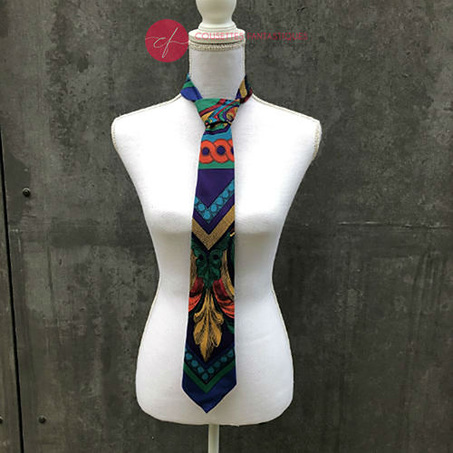 Une cravate fabriquée à partir d'un foulard de soie rouge, bleu, vert, jaune... et au motif rococco.