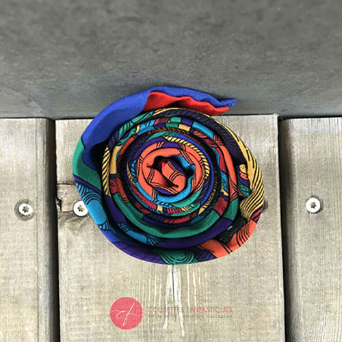 Une cravate fabriquée à partir d'un foulard de soie rouge, bleu, vert, jaune... et au motif rococco.