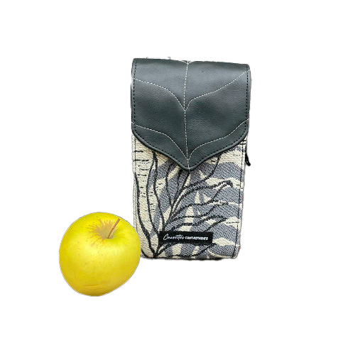 Un compagnon fabriqué à partir d'une écharpe de portage blanche, noire et grise avec des motifs de feuilles tropicales et un simili cuir noir.
