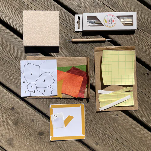 Le contenu de la boîte du Kit DIY Découverte Kinusaiga : son support, ses adhésifs, son dos cartonné, ses outils, son motif et son lot de chutes de tissus colorées.