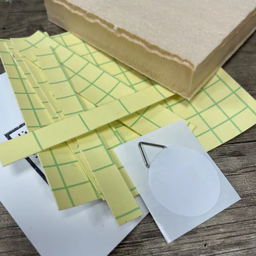 Le contenu de base du Kit Recharge Kinusaiga : sa plaque, ses adhésifs et le dos carton avec attache.