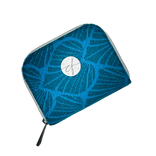 Un porte-cartes-et-monnaie zippé fabriqué avec un coupon d'écharpe de portage à motif de feuilles vert forêt et turquoise avec des paillettes.