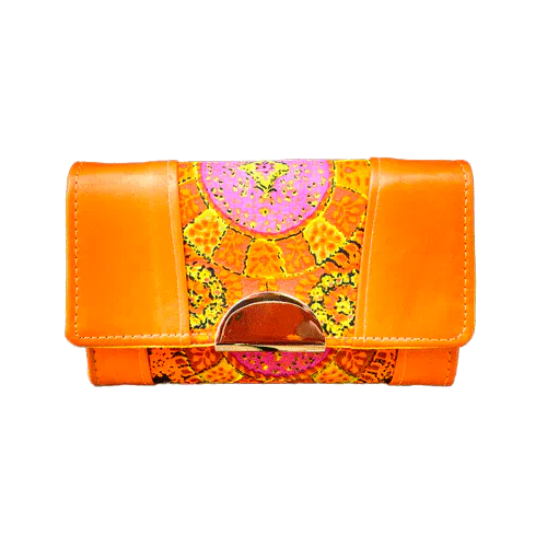 Un portefeuille fabriqué en cuir d'agneau orange et en tissu vintage multicolore en rayonne, dans des tons d'orange, de jaune et de rose.