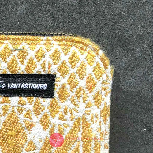 Un petit porte-cartes et porte-monnaie zippé en tissu gris brodé de motifs floraux scandinaves bleus, rouges et blancs.