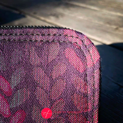 Un petit porte-cartes et porte-monnaie zippé réalisé en tissu dans des nuances de violet, prune, rose... avec un motif de gouttelettes, et en cuir d'agneau noir.