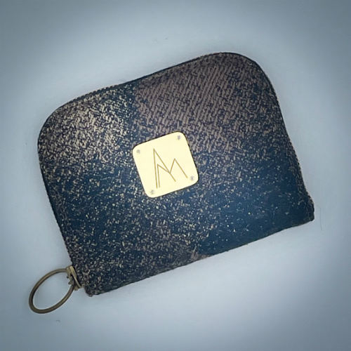 Un petit porte-cartes et monnaie zippé fait avec du tissu d'écharpe de portage noir, marron et beige avec un motif abstrait rond.