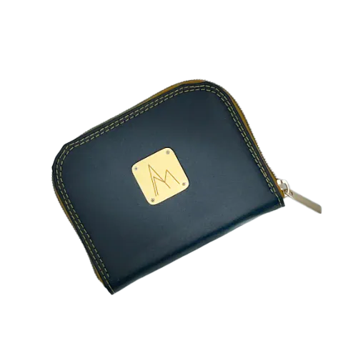 Un petit porte-cartes et porte-monnaie zippé en matériau à base de raisin, de couleur noir satiné et comme pailleté, avec une doublure rouge irisé de reflets violines et une popeline au motif floral en noir et blanc.