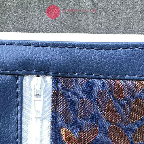 A mini zippered coin purse made up of a patchwork of different materials: royal blue faux leather, golden faux leather, shiny bronze fabric, and blue and bronze wrap fabric with a pattern of small droplets.