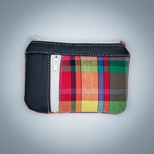 Un petit porte-monnaie zippé fabriqué à partir d'un patchwork de différents matériaux : une toile de Madras et du cuir d'agneau noir.