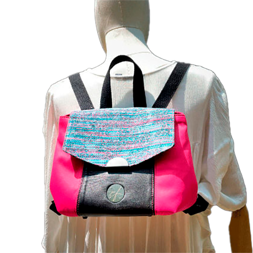 Un sac à dos fabriqué avec un tissu d'ameublement rose vif, du cuir noir et un coupon d'écharpe de portage au motif floral.