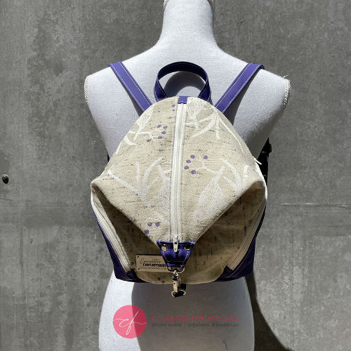 Un sac à dos confectionné en neoprene violet et en tissu d'écharpe dans des tons écru et violet, au motif d'oiseaux dans des branches.