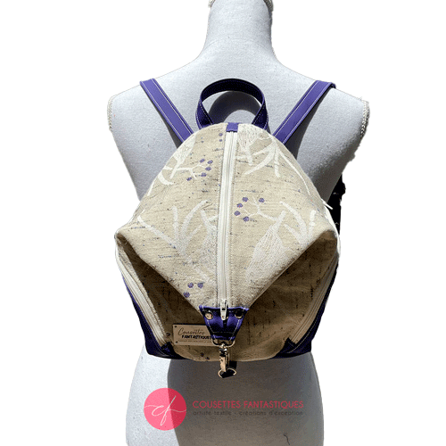Un sac à dos confectionné en neoprene violet et en tissu d'écharpe dans des tons écru et violet, au motif d'oiseaux dans des branches.