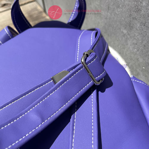 Un sac à dos confectionné en neoprene violet et en tissu d'écharpe dans des tons écru et violet, au motif d'oiseaux dans des branches.