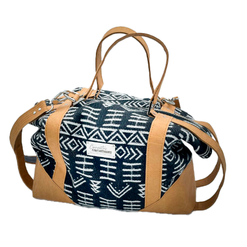 Un petit sac de voyage fabriqué en papier lavable couleur caramel, une écharpe de portage à motif géométrique noir et blanc, et de la popeline grise.