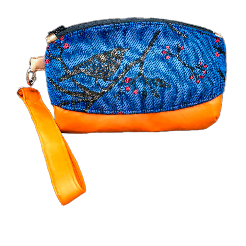 Une petite pochette zippée cousue en cuir orange et une écharpe de portage bleu électrique, noir et rouge avec un motif d'oiseaux dans des branches'.