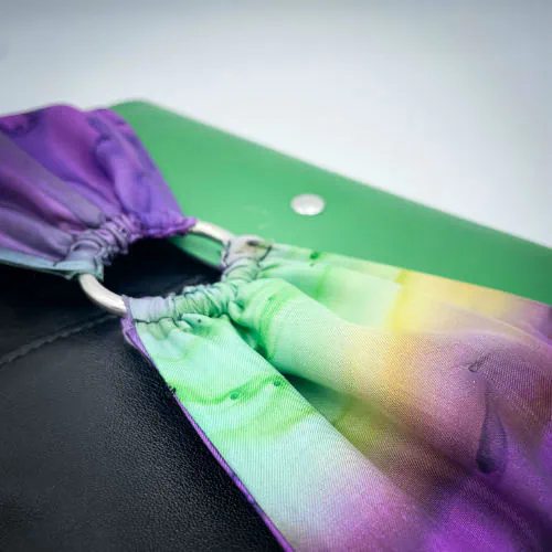 Une pochette à rabat cousue dans un voile de soie jaune, vert et violet et associé à des cuirs noir, vert et jaune.
