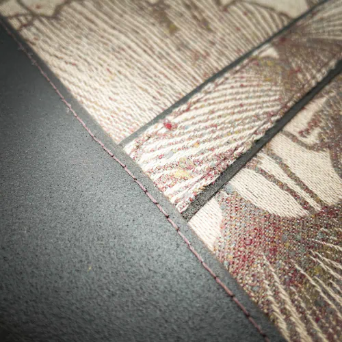 Une pochette zippée cousue dans une sorte de peau pommelée de couleur brun et un coupon d'écharpe de portage au motif de Ginkgo Biloba bruns sur fond rose poudré.