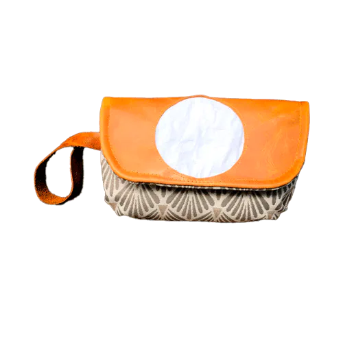 Une pochette à rabat cousue en cuir caramel, damas blanc et tissu à motifs vintage beige et gris, doublée de toile taupe.