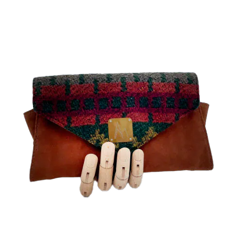 Un portefeuille fabriqué à partir de en suédine alezan et drap laine au motif géométrique, avec une doublure en viscose à motif géométrique.