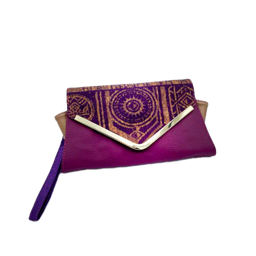 Un portefeuille fabriqué à partir de chutes de tissu provenant d'écharpes à motif géométrique violet et jaune, combinées à des simili violets et dorés à l'extérieur, et à une toile légère de lin moutarde et du satin violet profond à l'intérieur.