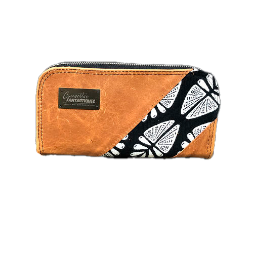 Un portefeuille fabriqué à partir de cuir caramel et d'un coupon d'écharpe de portage en noir et blanc au motif géométrique inspiré par la nature à l'extérieur, et de popeline noire à l'intérieur.